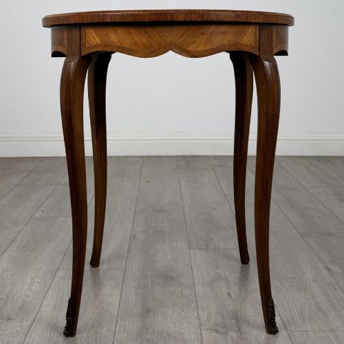fig 4. A circular French Louis XV style lamp table featuring slender cabriole legs, marquetry wood grain pattern, an undulating apron, and metal sabot feet.