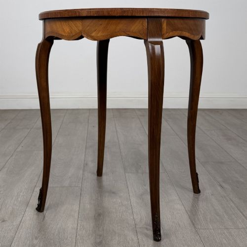 fig 5. A circular French Louis XV style lamp table featuring slender cabriole legs, marquetry wood grain pattern, an undulating apron, and metal sabot feet.