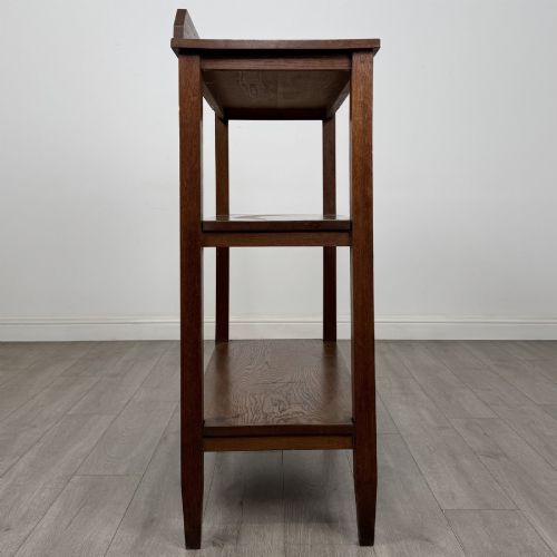 fig 6. An antique Edwardian dark oak buffet featuring three open rectangular shelves supported by straight tapered legs.