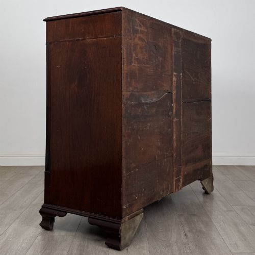 fig 3. An 18th-century Georgian mahogany chest of drawers featuring inlaid stringing along the top frieze, two short drawers above three long drawers, brass swan-neck handles, fluted pilasters, and bracket feet.