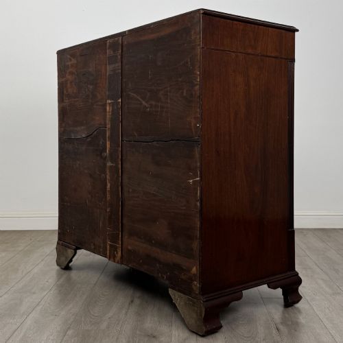 fig 5. An 18th-century Georgian mahogany chest of drawers featuring inlaid stringing along the top frieze, two short drawers above three long drawers, brass swan-neck handles, fluted pilasters, and bracket feet.
