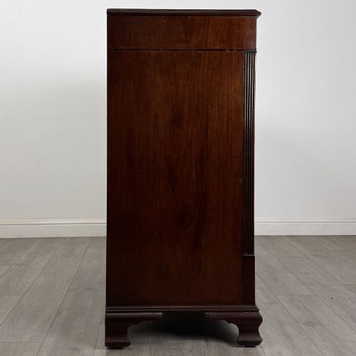 fig 6. An 18th-century Georgian mahogany chest of drawers featuring inlaid stringing along the top frieze, two short drawers above three long drawers, brass swan-neck handles, fluted pilasters, and bracket feet.