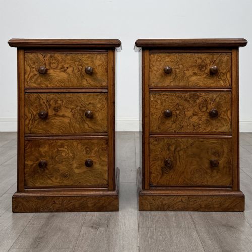 fig 1. A pair of Victorian burr walnut bedside cabinets featuring three drawers each with turned wooden knobs and a plinth base.