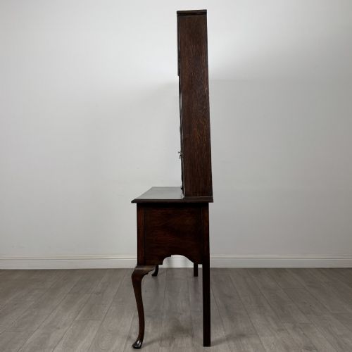 fig 2. A dark oak Queen Anne style dresser featuring an open-shelf upper rack with side cupboards above two drawers supported by cabriole legs.