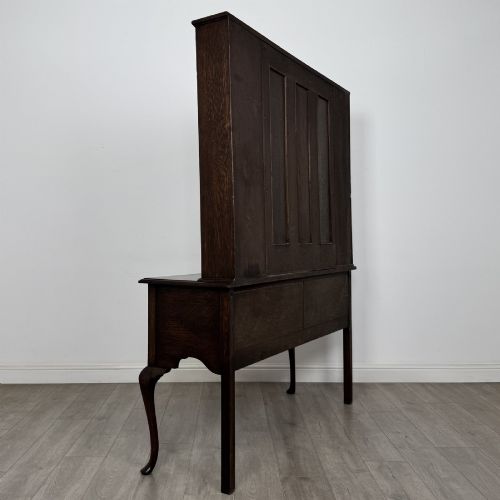 fig 3. A dark oak Queen Anne style dresser featuring an open-shelf upper rack with side cupboards above two drawers supported by cabriole legs.