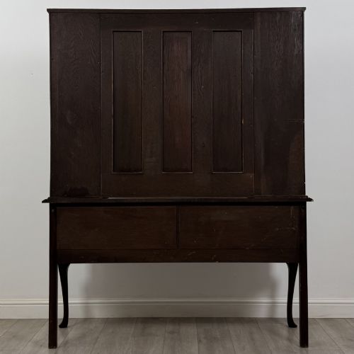 fig 4. A dark oak Queen Anne style dresser featuring an open-shelf upper rack with side cupboards above two drawers supported by cabriole legs.