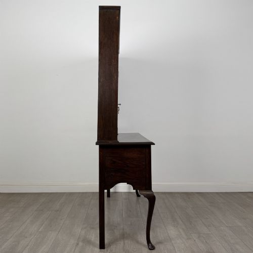 fig 6. A dark oak Queen Anne style dresser featuring an open-shelf upper rack with side cupboards above two drawers supported by cabriole legs.