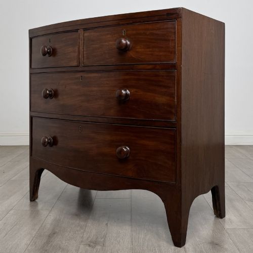fig 1. A 19th-century dark mahogany bow front chest of drawers featuring two short drawers above two long drawers with turned wooden handles and bracket feet.
