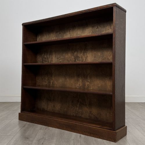 fig 2. A dark oak open bookcase featuring four tier adjustable shelves and carved moulding along the top frieze.