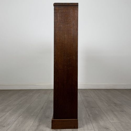 fig 3. A dark oak open bookcase featuring four tier adjustable shelves and carved moulding along the top frieze.