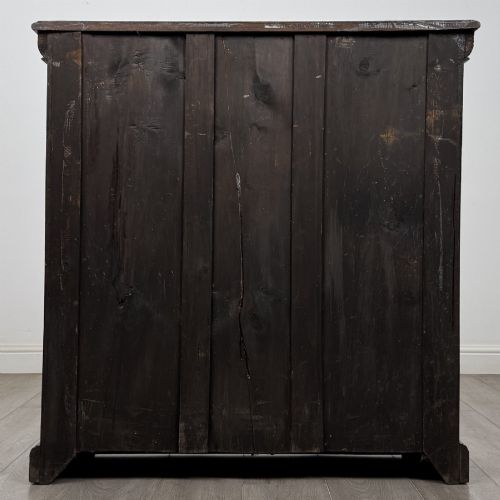 fig 5. A dark carved oak open bookcase featuring three shelf surfaces and pilasters detailed with foliate carvings and Green Man masks.