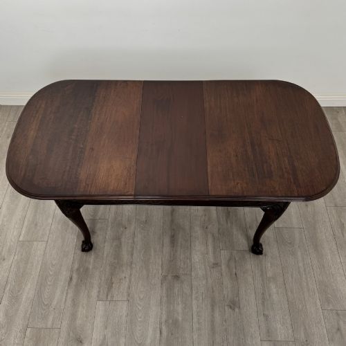 fig 5. An Edwardian mahogany extending dining table featuring a carved frieze and cabriole legs terminating in ball-and-claw feet.