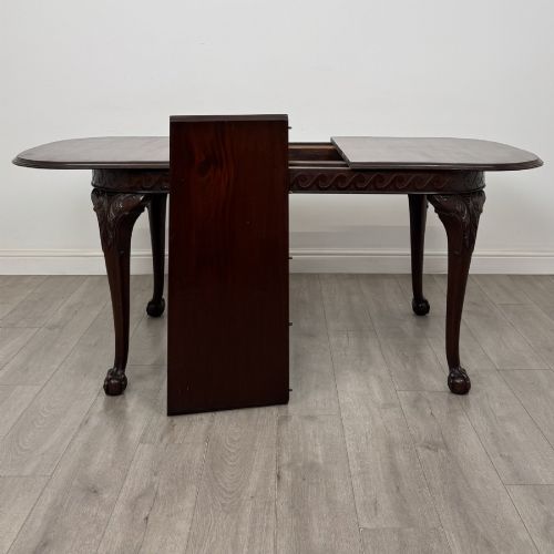 fig 6. An Edwardian mahogany extending dining table featuring a carved frieze and cabriole legs terminating in ball-and-claw feet.