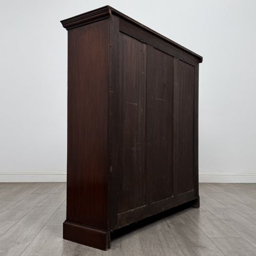 fig 4. An Edwardian dark mahogany open bookcase featuring three frieze drawers with brass drop handles and three adjustable wooden shelves above a plinth base.