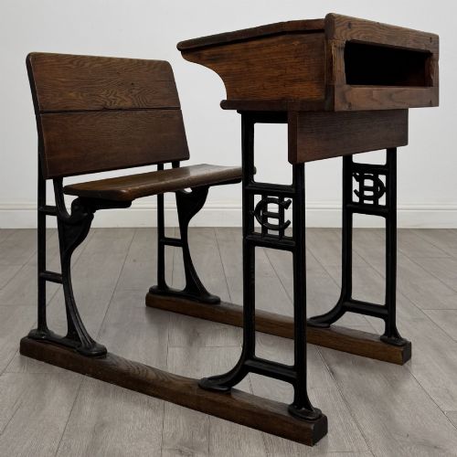 fig 6. An antique early 20th-century school desk featuring a sloped dark timber top with a storage compartment, attached to a black cast iron frame with an integrated bench seat.
