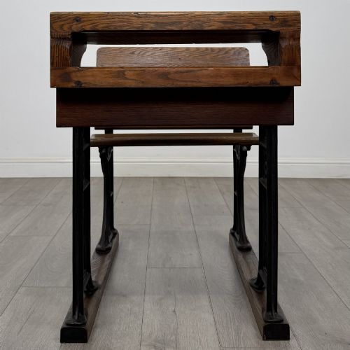 fig 7. An antique early 20th-century school desk featuring a sloped dark timber top with a storage compartment, attached to a black cast iron frame with an integrated bench seat.