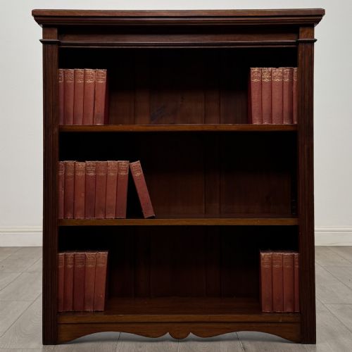 fig 1. A dark brown Victorian pine open bookcase featuring adjustable shelving, reeded side pilasters, and a shaped apron at the base.