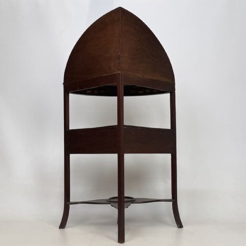 fig 2. A dark mahogany Georgian bow-front corner washstand featuring a curved splashback with a small upper shelf, a middle section with a central drawer flanked by dummy drawers, and splayed legs united by a circular stretcher.