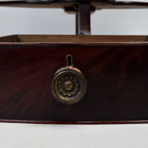 fig 6. A dark mahogany Georgian bow-front corner washstand featuring a curved splashback with a small upper shelf, a middle section with a central drawer flanked by dummy drawers, and splayed legs united by a circular stretcher.