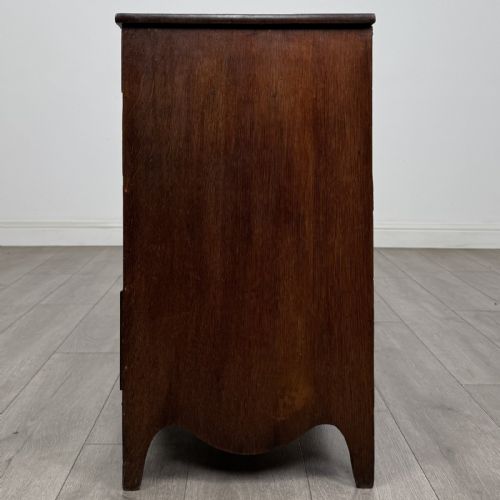 fig 2. A 19th-century oak chest of drawers featuring four graduated drawers with ornate brass backplate drop handles, keyhole escutcheons, and bracket feet.
