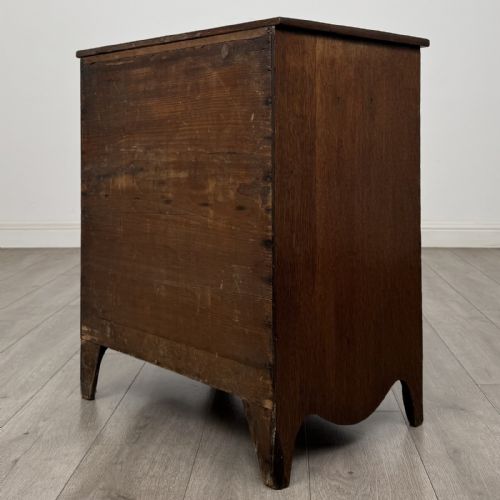 fig 5. A 19th-century oak chest of drawers featuring four graduated drawers with ornate brass backplate drop handles, keyhole escutcheons, and bracket feet.
