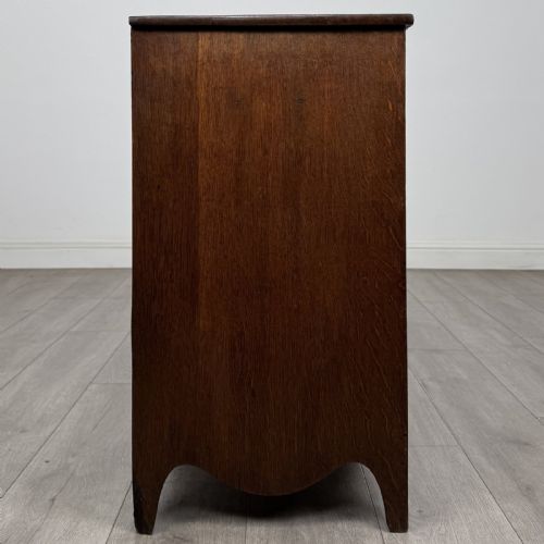 fig 6. A 19th-century oak chest of drawers featuring four graduated drawers with ornate brass backplate drop handles, keyhole escutcheons, and bracket feet.