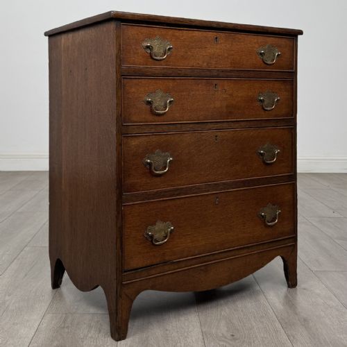 fig 7. A 19th-century oak chest of drawers featuring four graduated drawers with ornate brass backplate drop handles, keyhole escutcheons, and bracket feet.