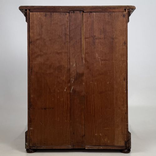 fig 4. A small Victorian pitch pine cupboard featuring twin panelled doors with pronounced wood grain, a moulded top, and a plinth base on small bun feet.