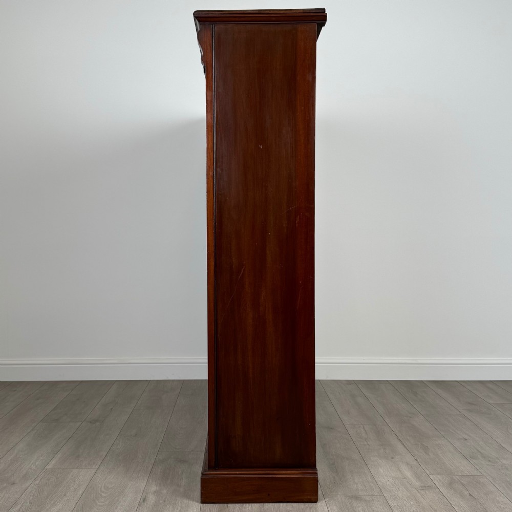 A front-facing view of a large, dark brown mahogany open bookcase featuring a central vertical divider and multiple fixed shelves. View III
