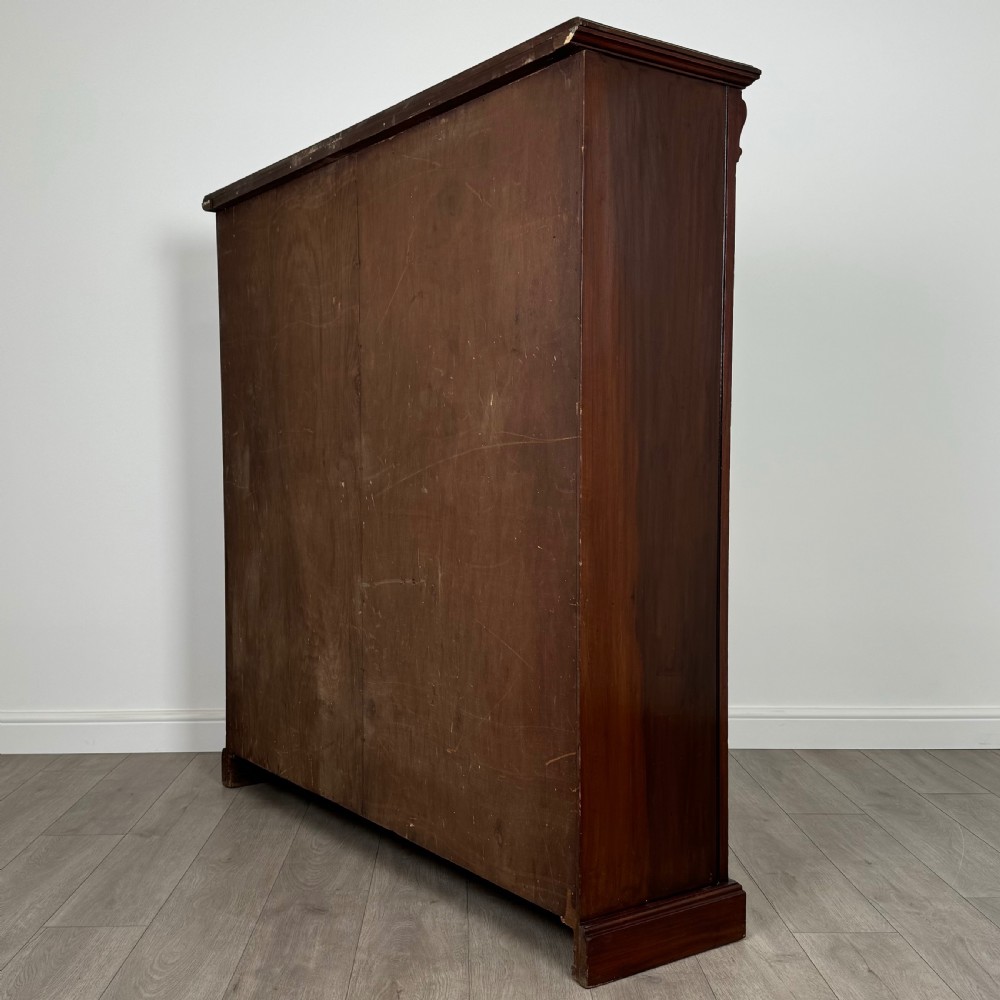 A front-facing view of a large, dark brown mahogany open bookcase featuring a central vertical divider and multiple fixed shelves. View VI