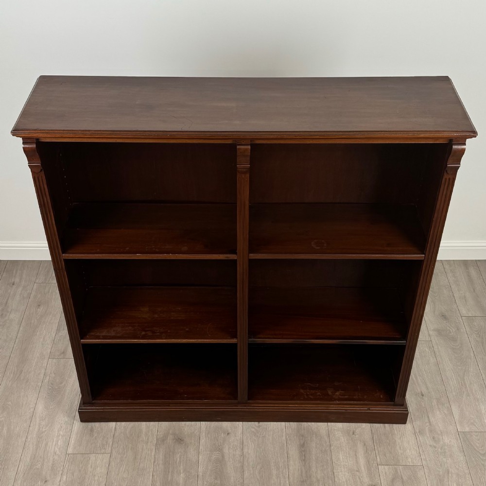 A front-facing view of a large, dark brown mahogany open bookcase featuring a central vertical divider and multiple fixed shelves. View IX