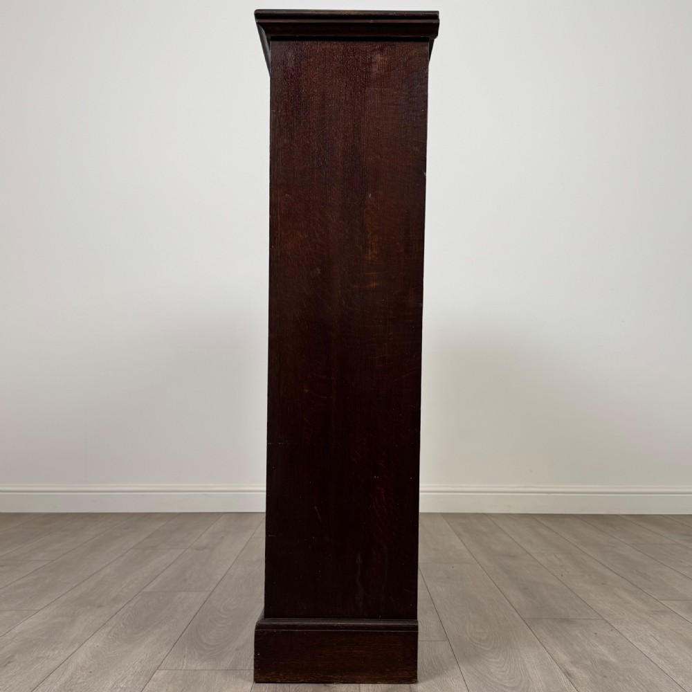 An antique dark oak open bookcase with four shelves containing rows of vintage books. View IV