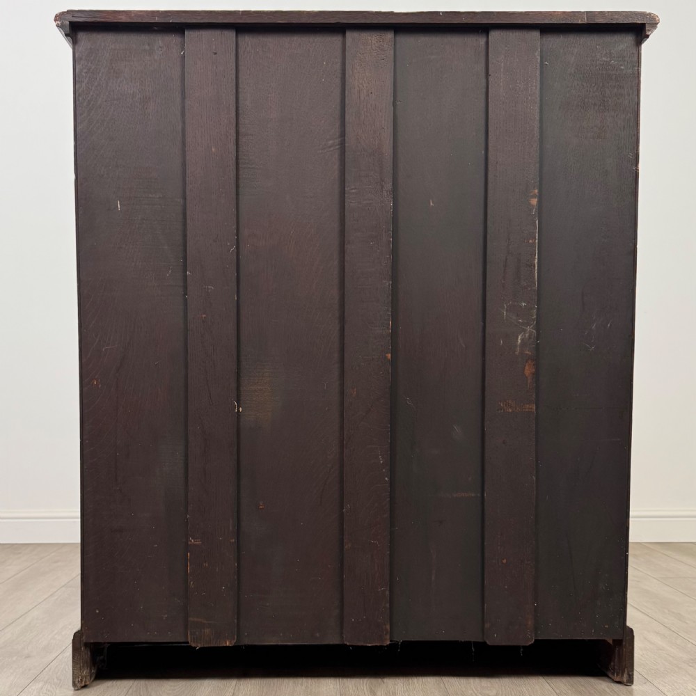 An antique dark oak open bookcase with four shelves containing rows of vintage books. View VI