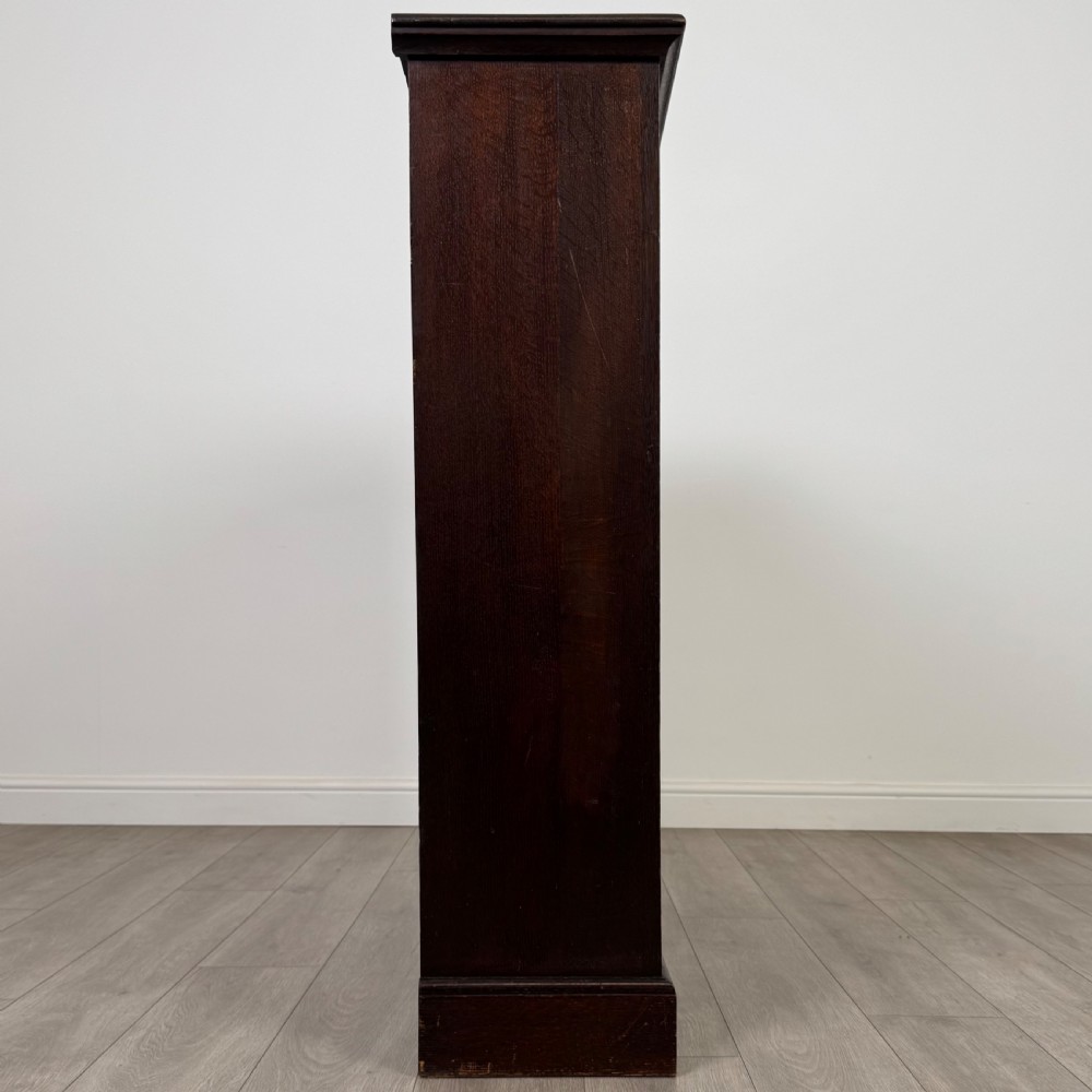 An antique dark oak open bookcase with four shelves containing rows of vintage books. View VIII