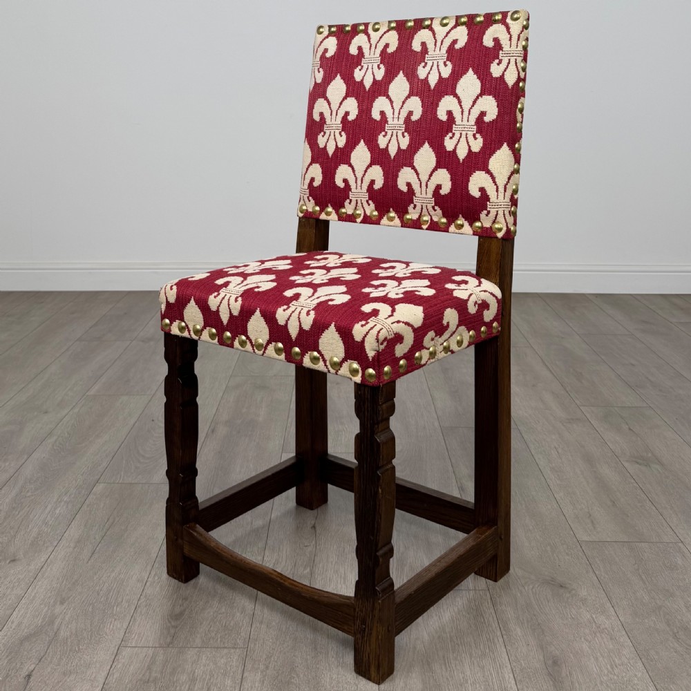 A set of fourteen dark oak dining chairs with red and cream fleur-de-lis patterned upholstery and brass stud trim. View II