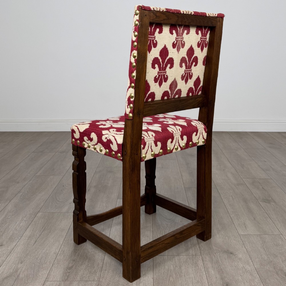A set of fourteen dark oak dining chairs with red and cream fleur-de-lis patterned upholstery and brass stud trim. View III
