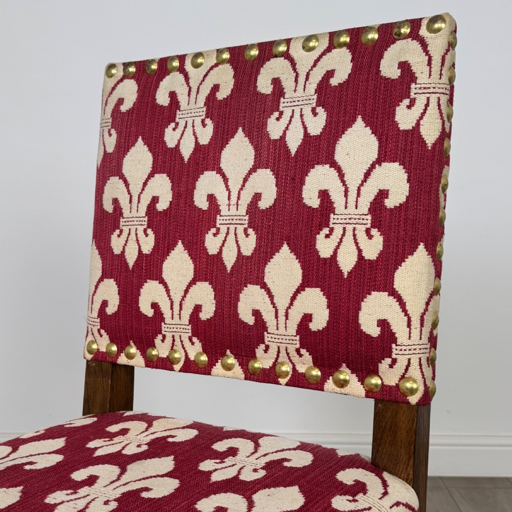 A set of fourteen dark oak dining chairs with red and cream fleur-de-lis patterned upholstery and brass stud trim. View IV