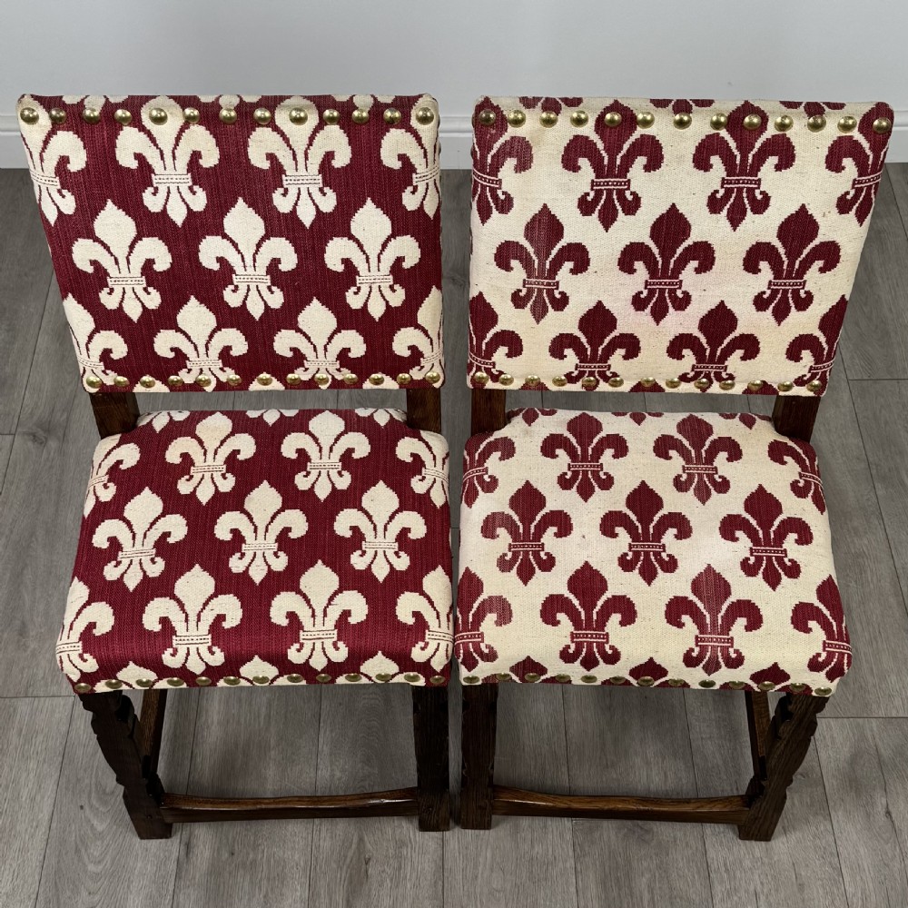A set of fourteen dark oak dining chairs with red and cream fleur-de-lis patterned upholstery and brass stud trim. View VIII