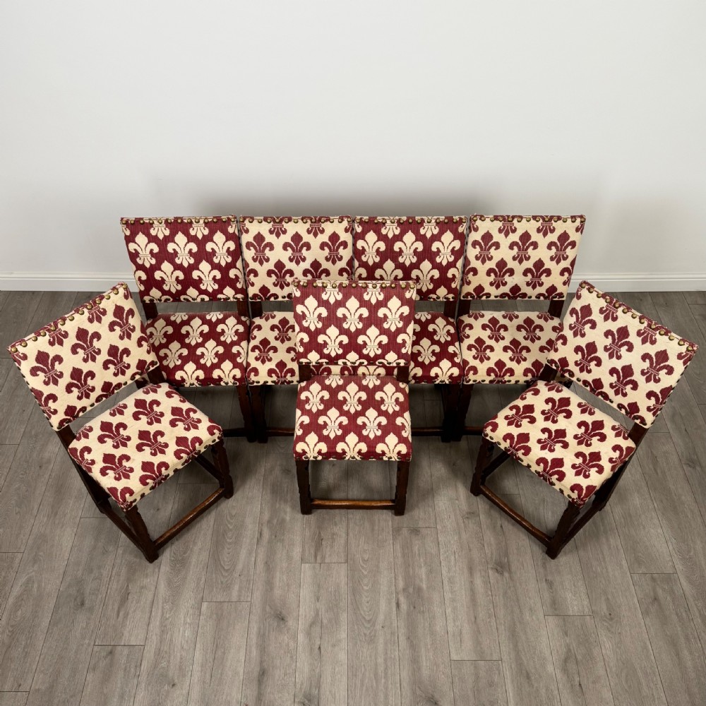 A set of fourteen dark oak dining chairs with red and cream fleur-de-lis patterned upholstery and brass stud trim. View IX