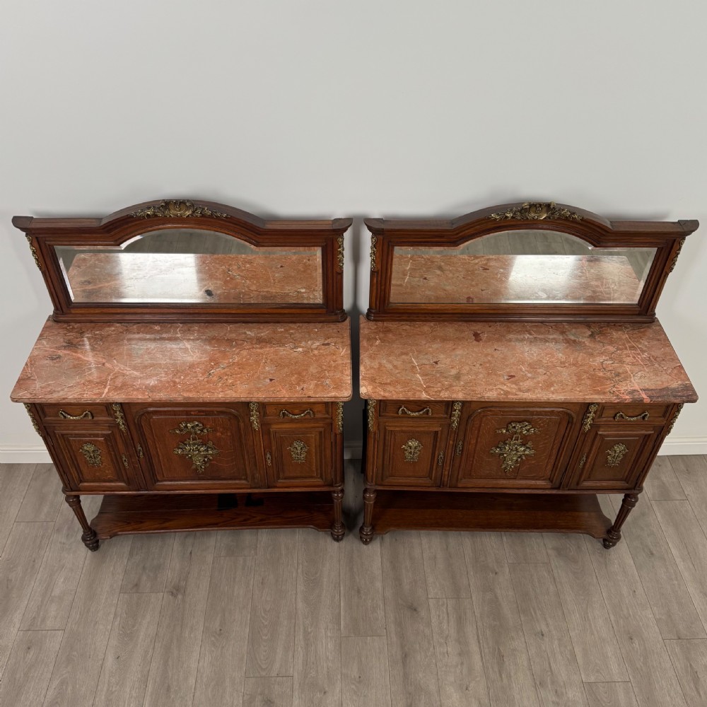 A pair of 19th-century French dark wood cabinets featuring pink marble tops, mirrored upper backs, gilded metal mounts, and lower open shelves. View XII