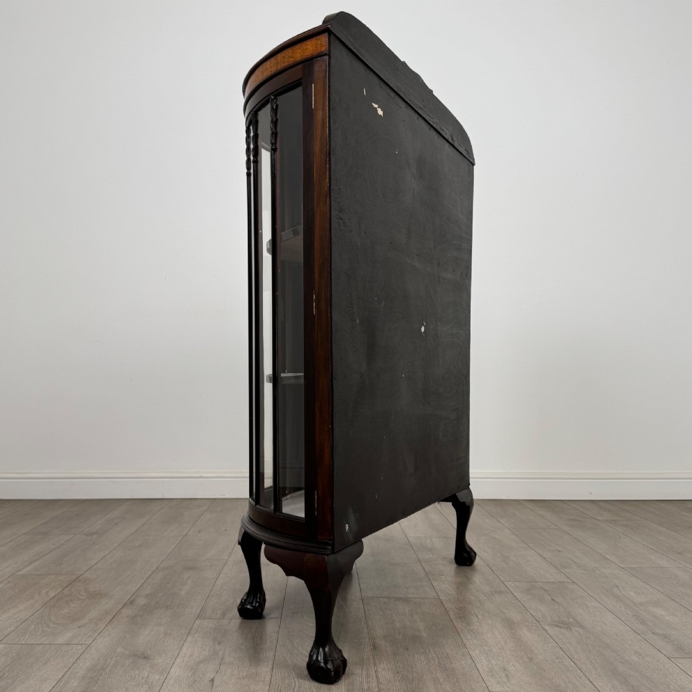 An early twentieth-century mahogany bow-front display cabinet featuring curved glass doors, vertical glazing bars, internal shelves, and cabriole legs with ball-and-claw feet. View V