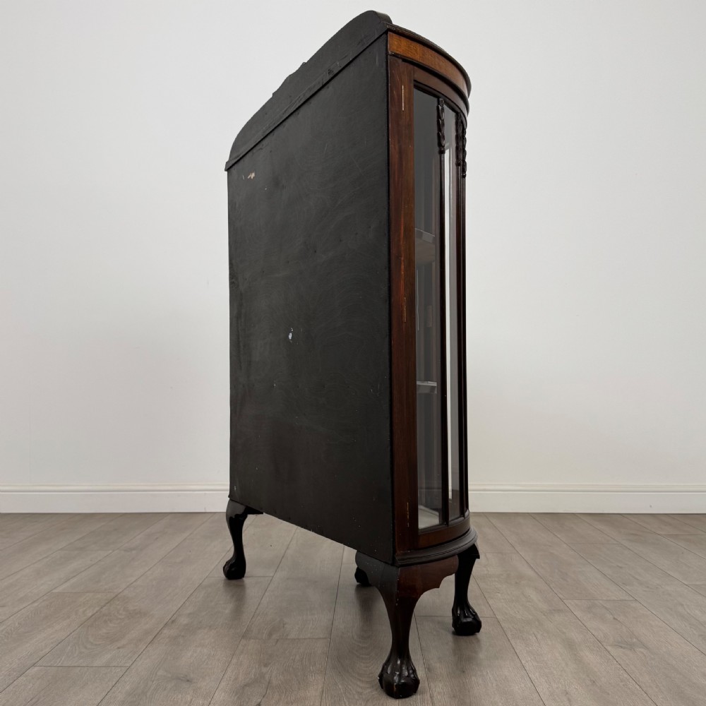 An early twentieth-century mahogany bow-front display cabinet featuring curved glass doors, vertical glazing bars, internal shelves, and cabriole legs with ball-and-claw feet. View VII