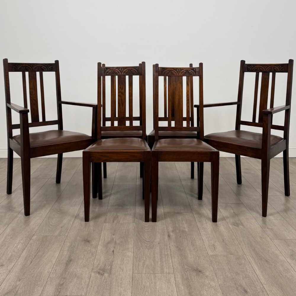 Dark oak trestle dining table paired with six matching carved oak chairs with dark leather seats. View II
