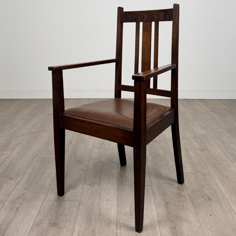 Dark oak trestle dining table paired with six matching carved oak chairs with dark leather seats. View III