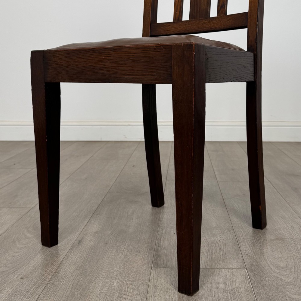 Dark oak trestle dining table paired with six matching carved oak chairs with dark leather seats. View VII