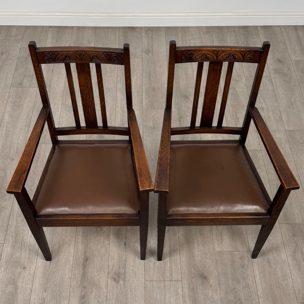 Dark oak trestle dining table paired with six matching carved oak chairs with dark leather seats. View IX