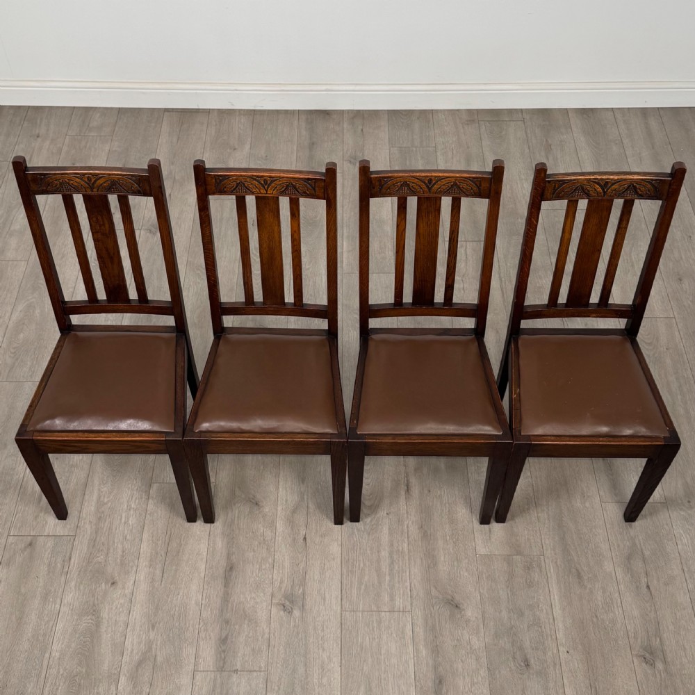 Dark oak trestle dining table paired with six matching carved oak chairs with dark leather seats. View X
