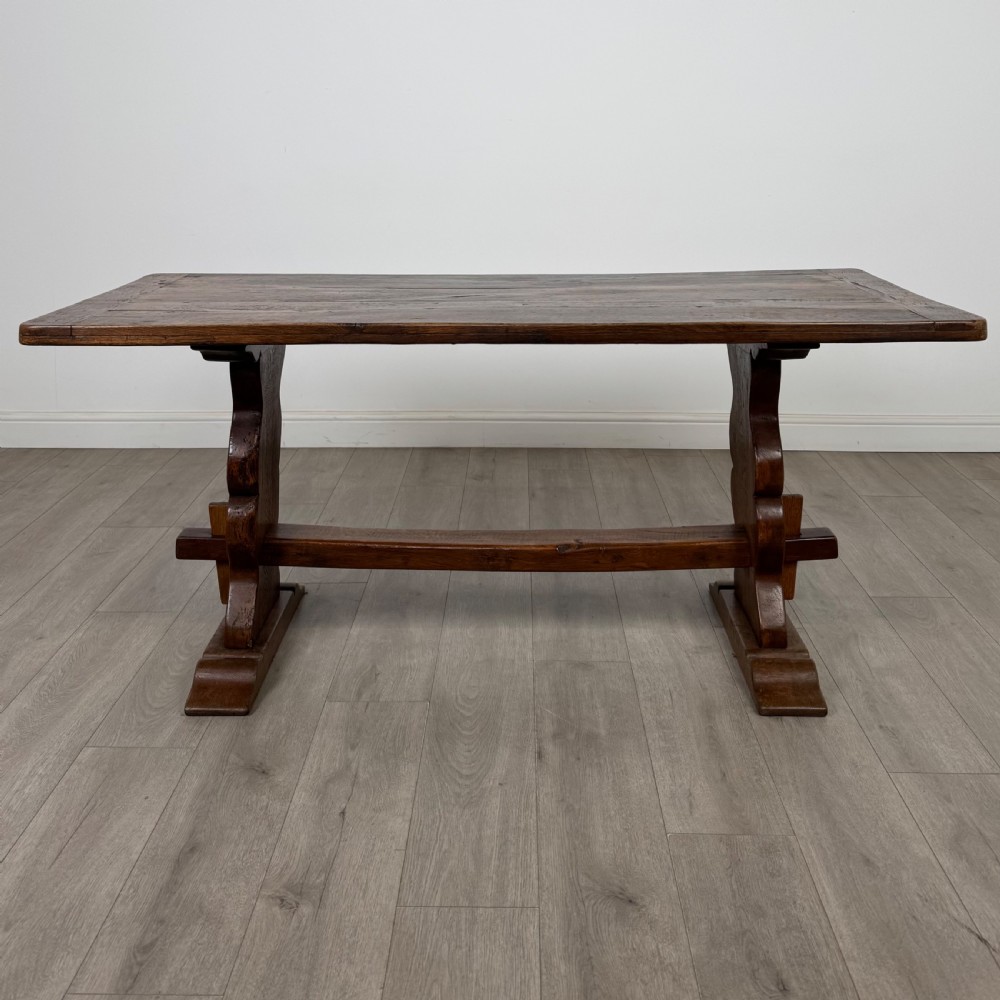 Dark oak trestle dining table paired with six matching carved oak chairs with dark leather seats. View XII