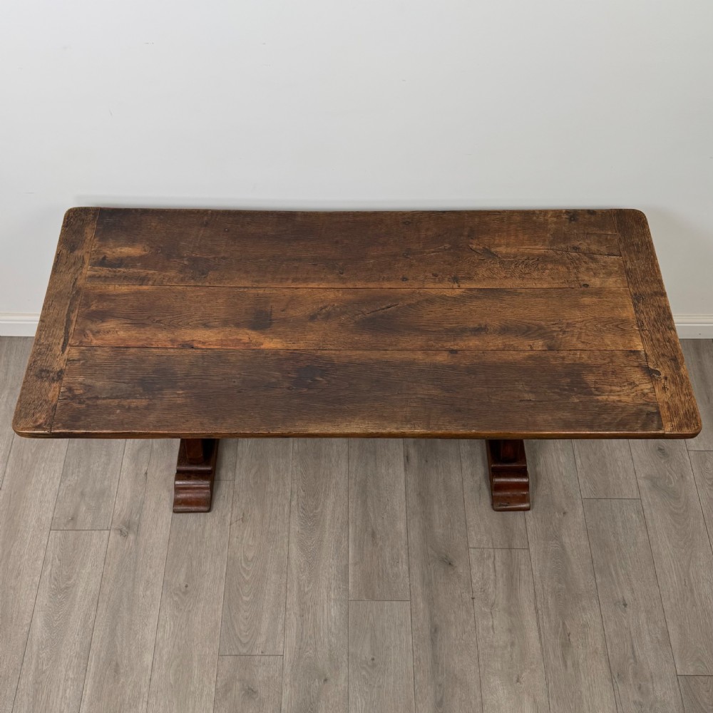 Dark oak trestle dining table paired with six matching carved oak chairs with dark leather seats. View XIV
