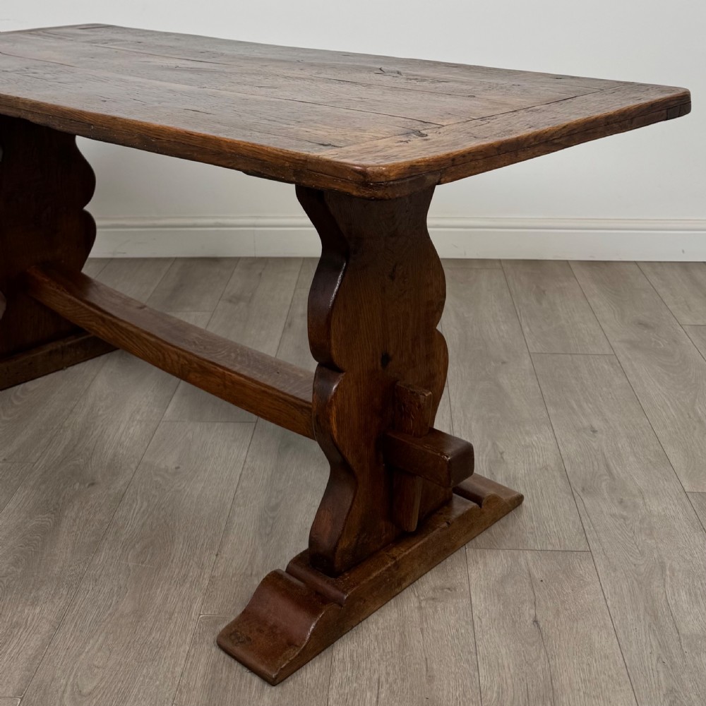 Dark oak trestle dining table paired with six matching carved oak chairs with dark leather seats. View XV